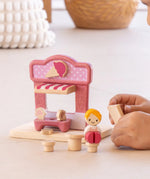 Child playing with the PlanToys ice cream shop wooden toy playset, placing the advert board into the scene.