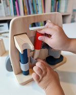 Close up of a hand pulling out a tool from the Plan Toys plastic free wooden carpenter role play toy set