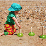 A child on the beach playing with the PlanToys Meadow Ring Toss. 
