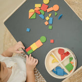 Overhead view of a child creating a colourful pattern using the wooden pieces from the PlanToys Mosaic wooden pattern making toy.