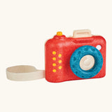 PlanToys my first wooden camera with a red body and blue lens. Features a working shutter button and cotton carry loop