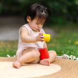 Child playing with the PlanToys Nesting Cylinders 3 piece wooden toy. Red, yellow and blue coloured wooden cylinder shaped wooden pieces that nest inside each other. 