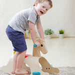 A child standing on the side of the PlanToys Palomino Rocking Horse. 