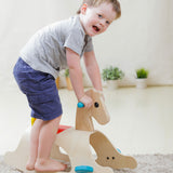 A child standing on the side of the PlanToys Palomino Rocking Horse. 