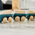 Plan toys plastic free wooden hybrid train toy on a grey wooden floor