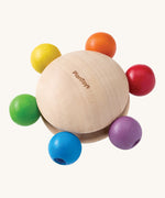 Plan Toys Pull & Grasp wooden baby toy - a wooden disk with rainbow grasping beads.