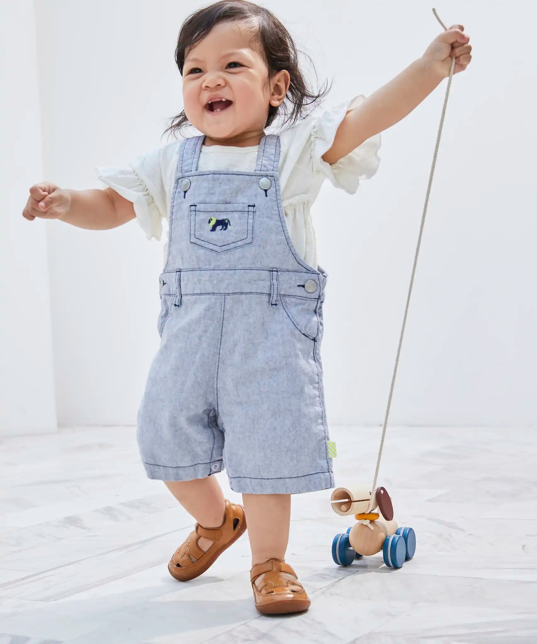 Child pulling the PlanToys push and pull puppy wooden toy by the string attachement.