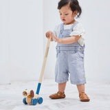 Child pushing along the PlanToys push and pull puppy wooden toy with the screw in stick attached. 