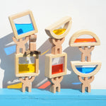 The PlanToys Water Blocks stacked up on the Bajo mendelsons placed on a blue painted surface against a white wall. 
