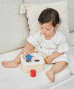 Child playing with the PlanToys shape and sort it out bin wooden shape sorter toy. 