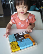 Girl looking at the Plan Toys eco-friendly wooden animal figures jigsaw puzzle game on a white table