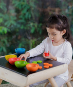 A child sat at the PlanToys table and chair playing with the Plan Toys Sort & Count Cups. 