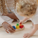 Child playing with the PlanToys sorting boat wooden shape sorting toy placing the orange triangle pieces into the frame.