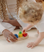 Child playing with the PlanToys sorting boat wooden shape sorting toy placing the orange triangle pieces into the frame.