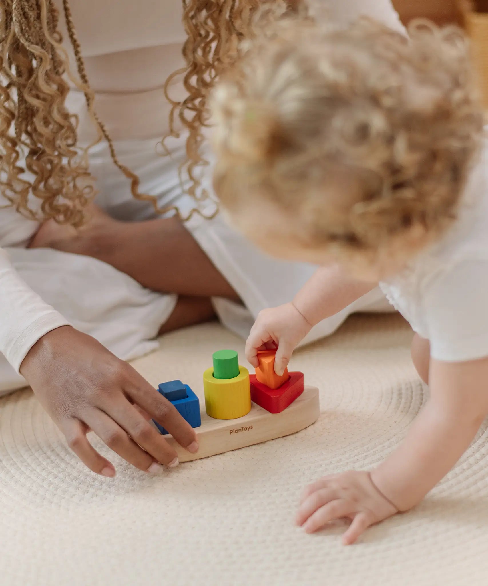Child playing with the PlanToys sorting boat wooden shape sorting toy placing the orange triangle pieces into the frame.