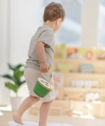 Child carrying the PlanToys geo sorting bucket wooden shape sorting toy. 