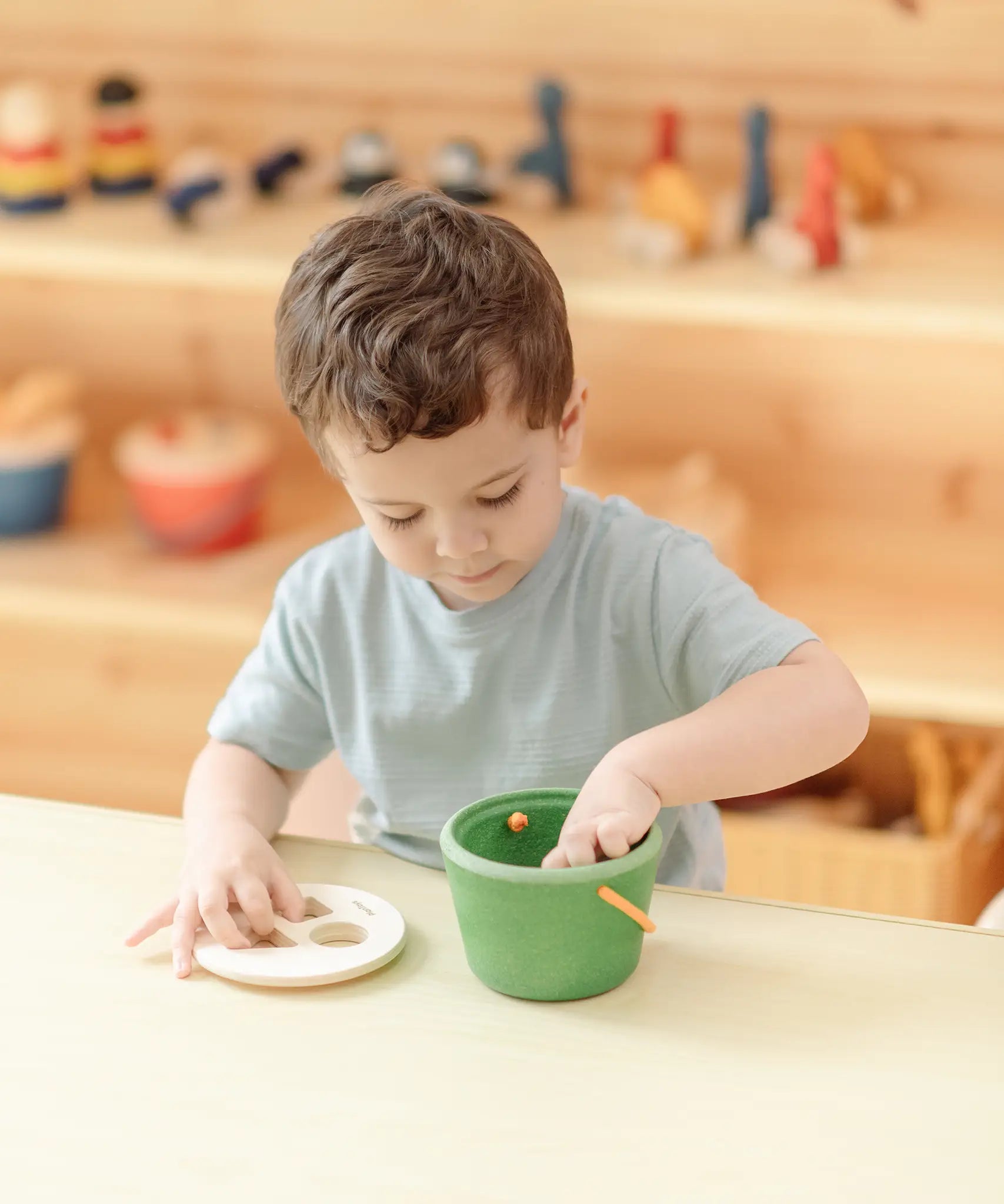 Child taking the wooden blocks out of the PlanToys geo sorting bucket wooden shape sorting toy. 