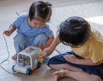 Two young children playing with a  PlanToys Sorting Bus Baby Toy.