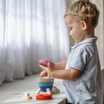 A child playing playing with the PlanToys Stacking Rocket Baby Toy, they have the pink piece in their hand. 