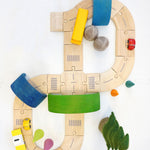 Plan Toys Standard Road System pictured from above with pieces of a Grimm's rainbow used as tunnels and bridges over the road