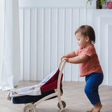 Child pushing a PlanToys stroller on a wooden floor