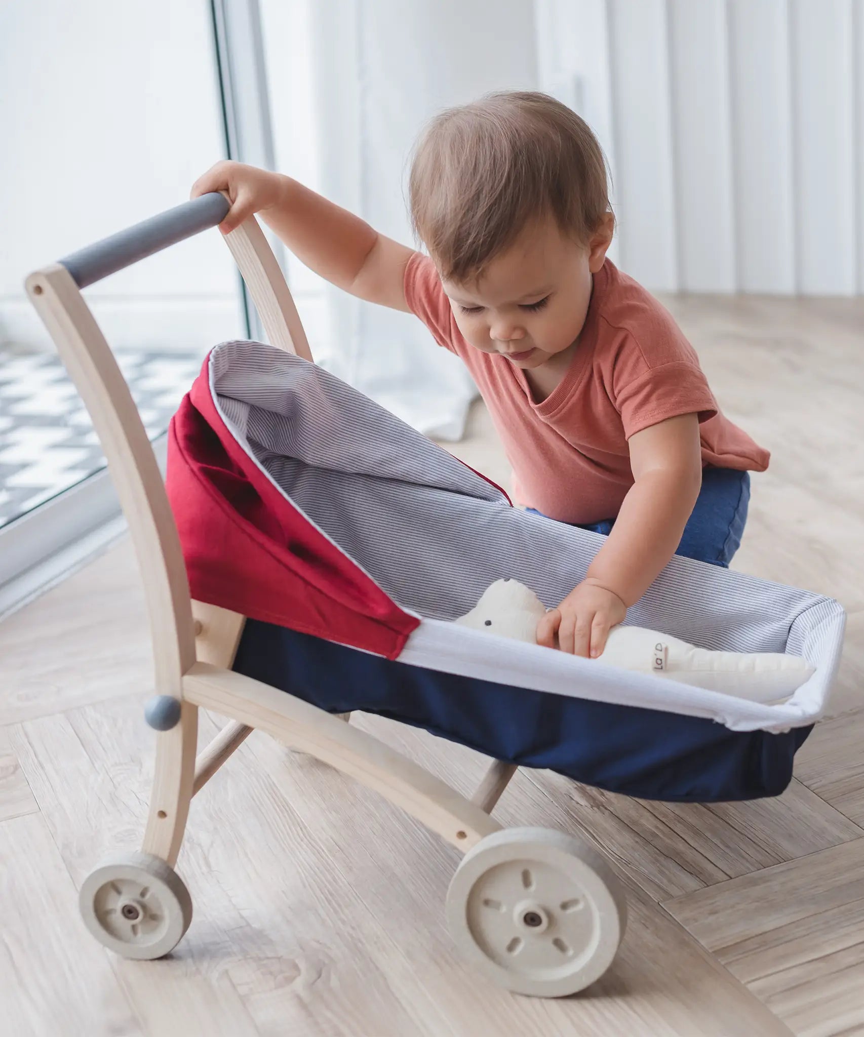 PlanToys stroller with a teddy bear lying inside
