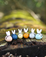 The bees from the PlanToys Bee Hives in the Orchard colour way placed in a line on a moss covered log. 