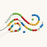 PlanToys threading beads wooden lacing toy. Rainbow coloured wooden beads threaded onto black and white laces.