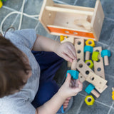 Child holding on a wooden screw from the PlanToys toolbox play set