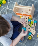 Child holding on a wooden screw from the PlanToys toolbox play set