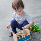 Child putting away wooden tolls and screws inside the PlanToys tool box play set