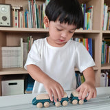 Child playing with the PlanToys blue wooden hybrid train on the PlanToys rubber railway and road. Three carriage train with magnetic connections. 