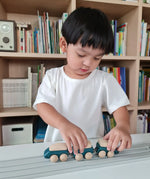 Child playing with the PlanToys blue wooden hybrid train on the PlanToys rubber railway and road. Three carriage train with magnetic connections. 