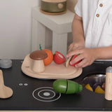 Child playing with the PlanToys wooden veggie set showing a tomato play food cut in half