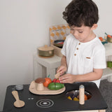 Child prepping veg from the PlanToys wooden veggie set on a play kitchen