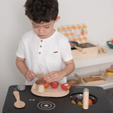Child playing with the PlanToys wooden veggie set on a play kitchen