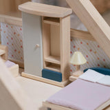A close up of the wardrobe from the PlanToys Bedroom Dolls House Furniture set placed in a room in a wooden dolls house. 