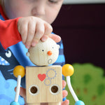 A child placing the round shocked expression head on the PlanToys Build a Robot toy. 