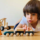 Child playing with the PlanToys wooden trains connecting different colours to each  other. 