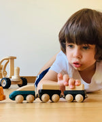 Child playing with the PlanToys wooden trains connecting different colours to each  other. 