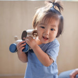 Child holding the PlanToys push and pull puppy wooden toy in their hands.