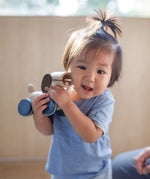 Child holding the PlanToys push and pull puppy wooden toy in their hands.