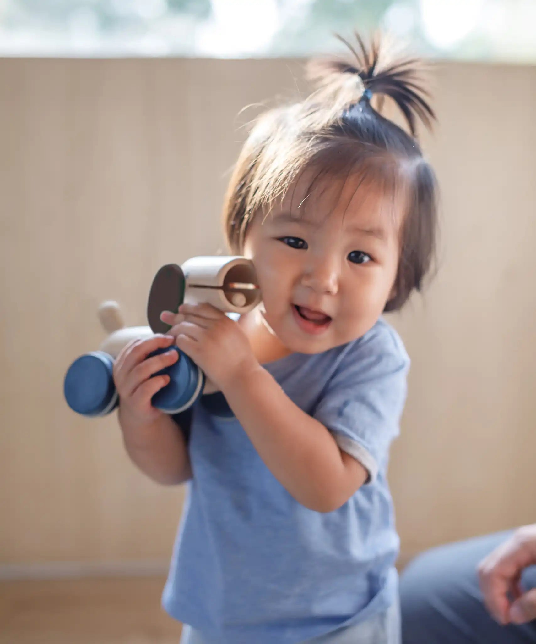 Child holding the PlanToys push and pull puppy wooden toy in their hands.