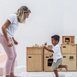 Mother and child playing next to different PlanToys wooden kitchen units