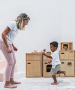 Mother and child playing next to different PlanToys wooden kitchen units