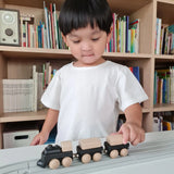 Child pushing the PlanToys black wooden classic toy train along a rubber railway track. 