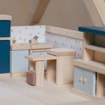 The PlanToys Kitchen Dolls House Furniture set placed in a wooden dolls house. 
