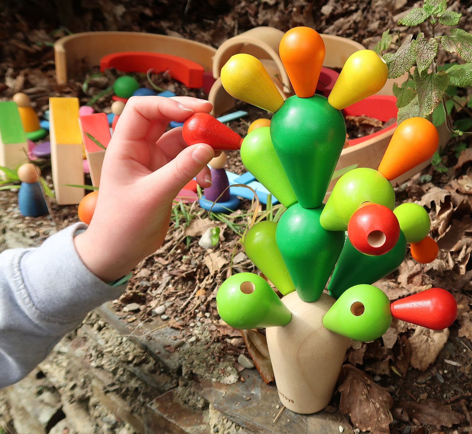 A close up the PlanToys Balancing Cactus being played with outdoors. 
