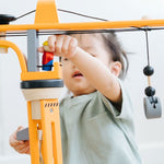 A close up of a child playing with the PlanToys PlanWorld Crane Set.