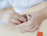A close up of a child's hands playing with the PlanToys Fractions Cubes.